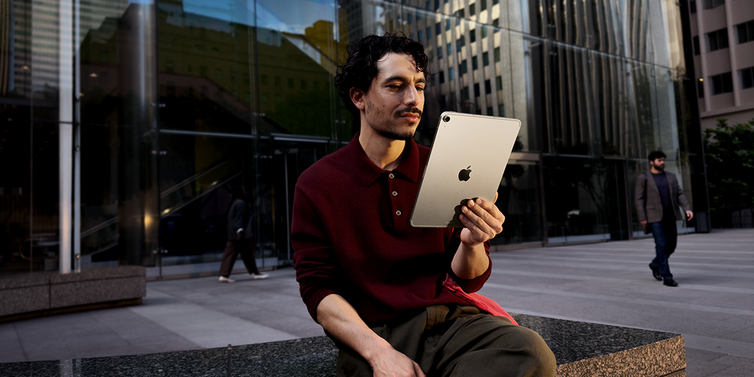 Man gebruikt iPad buiten aan modern kantoorgebouw.