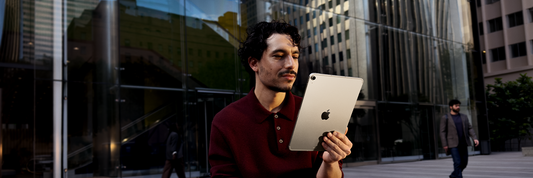 Man gebruikt iPad buiten aan modern kantoorgebouw.