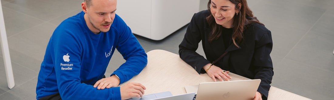 Een lab9-medewerker geeft uitleg aan een klant die een nieuwe MacBook Air koopt